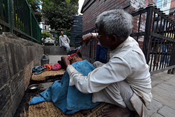 Street barber cutting the hair of a schoolboy on the streets of Kathmandu, Nepal — Stock Photo, Image