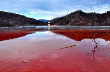 A flooded church in a toxic red lake. Water polluting by a copper mine clipart