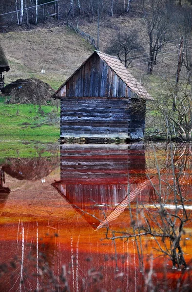 Een verlaten huis overspoeld door vervuild water van een koperen open-gegoten mijnen — Stockfoto