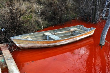 Abandoned boat in a contaminated red lake clipart