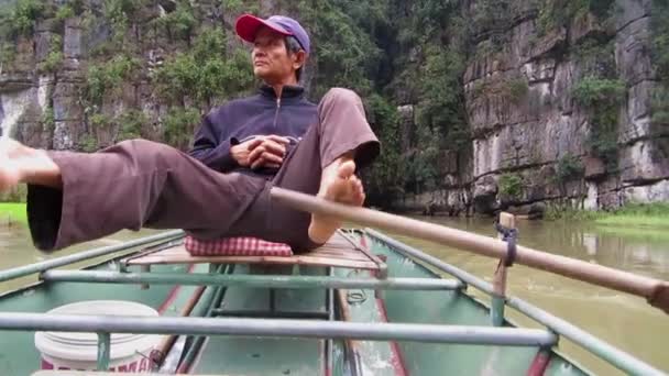 Paddler in Tam Coc paddle a tourist boat with his feet — Stock Video