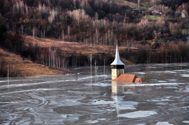 Abandoned church in a mud lake. Natural mining disaster with wat clipart