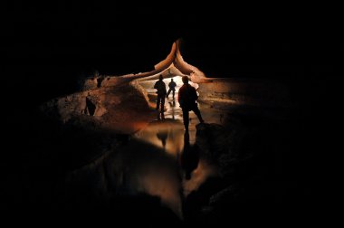 Spelunkers exploring an underground cave river clipart