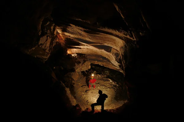 Spelunkers att utforska en underjordisk grotta — Stockfoto