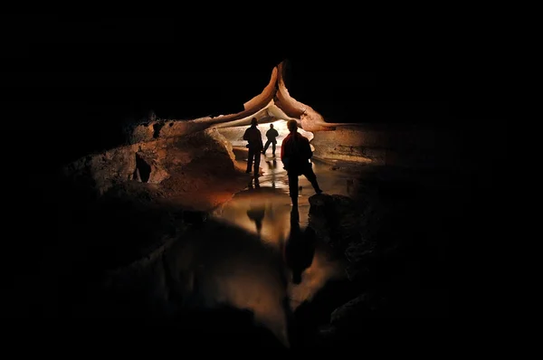 Espeleólogos explorando un río subterráneo Imagen de stock
