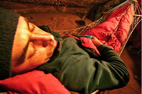 Jeskyňář odpočívá v houpací síti v jeskyni — Stock fotografie