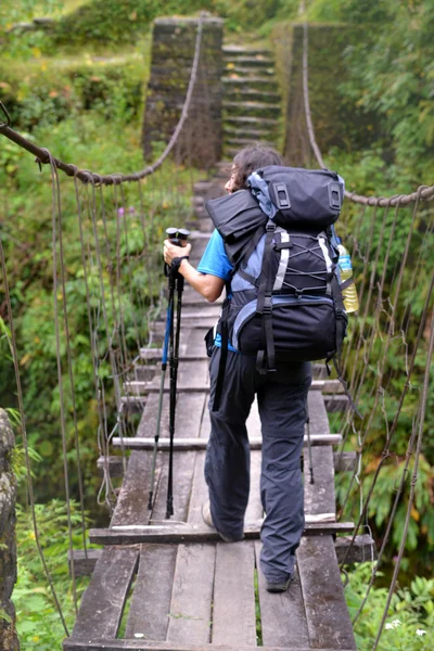 Trekker passing on a suspension bridge in the Himalayas — Stock Photo, Image