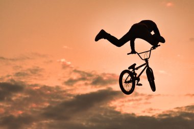 bmx bisiklet ile bir sıçrama yapan bir erkek silüeti 