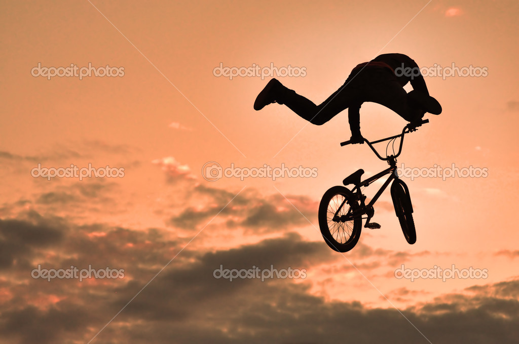 Silhouette of a man doing a jump with a bmx bike Stock Photo by