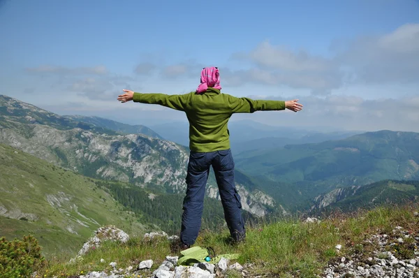 Junge Frau steht auf einer Klippe und blickt mit erhobenen Händen in den Himmel — Stockfoto