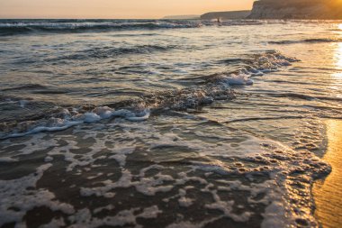 Kumlu plaj altın günbatımı sırasında yaklaşan dalgalar