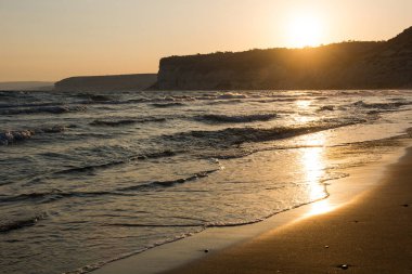 Altın gün batımında kumsala yaklaşan dalgalar