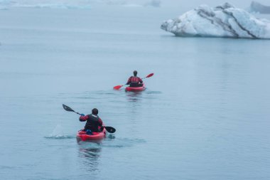 JOKULSARLON, ICELAND - 22 Mayıs 2019: Jokulsarlon buzulları arasındaki buzul gölünün dondurucu sularında bir kanoda kürek çeken adam