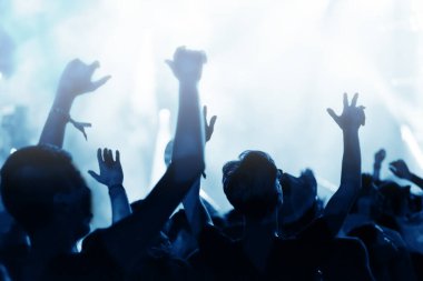 Bir müzik konseri seyircisi ellerini kaldırıyor, imajını düzeltiyor.