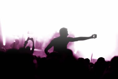 Parlak sahne ışıklarının önündeki bir konserde el silueti.