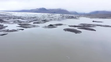 İzlanda 'daki Vatnajokull Ulusal Parkı' ndaki Svinafellsjokull gölünde eriyen buzdağlarının üzerinde uçuyor. Küresel ısınma ve iklim değişikliği çevre kavramı