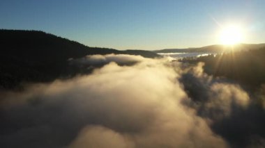  Sisli bir gölün havadan görünüşü. Gün doğumunda şafak vakti karanlık ışıklar, soğuk hava. Dağlarda bulutların üzerinde uçarken