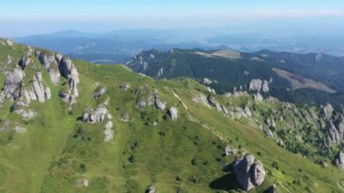İnsansız hava aracıyla yüksek dağ tortulu kayaların, tepelerin ve yeşil yamaçların havadan görünüşü. Ciucas dağları, Karpatlar, Romanya
