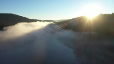  Sisli bir gölün havadan görünüşü. Gün doğumunda şafak vakti karanlık ışıklar, soğuk hava. Dağlarda bulutların üzerinde uçarken