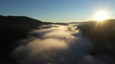  Sisli bir gölün havadan görünüşü. Gün doğumunda şafak vakti karanlık ışıklar, soğuk hava. Dağlarda bulutların üzerinde uçarken