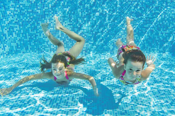 Niños felices sonriendo bajo el agua en la piscina Imágenes De Stock Sin Royalties Gratis
