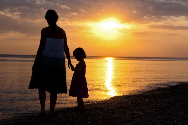 Familjen silhuetter på sunset beach — Stockfoto