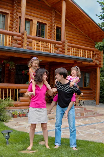 Feliz família sorridente perto de casa de madeira — Fotografia de Stock