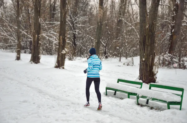 Šťastná žena aktivní běžec běhání venku v zasněženém parku v zimě — Stock fotografie