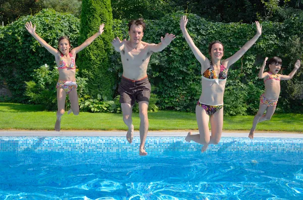 Happy family with kids jumping to swimming pool — Stock Photo, Image