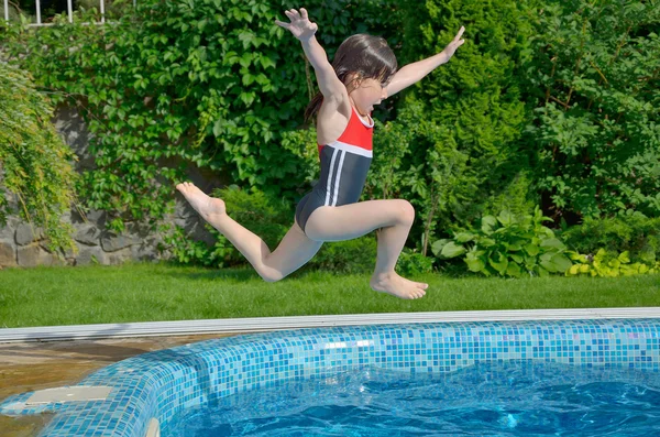 Happy active child jumps to swimming pool — Stock Photo, Image