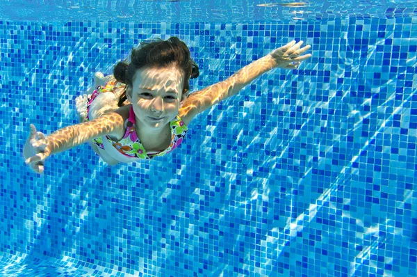 Šťastné aktivní dítě plave pod vodou v bazénu — Stock fotografie