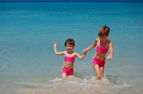 Two girls in swimming suits on tropical beach — Stock Photo, Image
