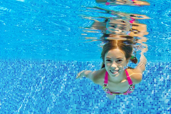 Criança ativa feliz nada debaixo d 'água na piscina — Fotografia de Stock