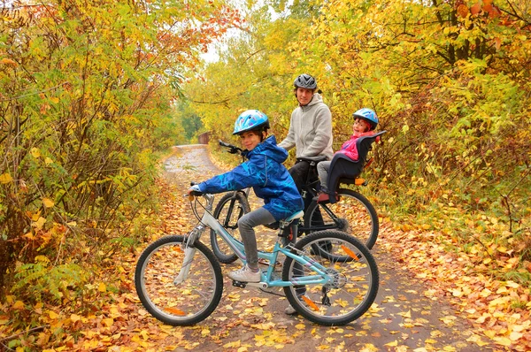 Happy family on bikes in autumn park — Stock Photo, Image