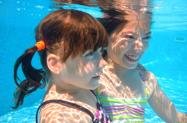 Happy girls swim underwater in pool — Stock Photo, Image