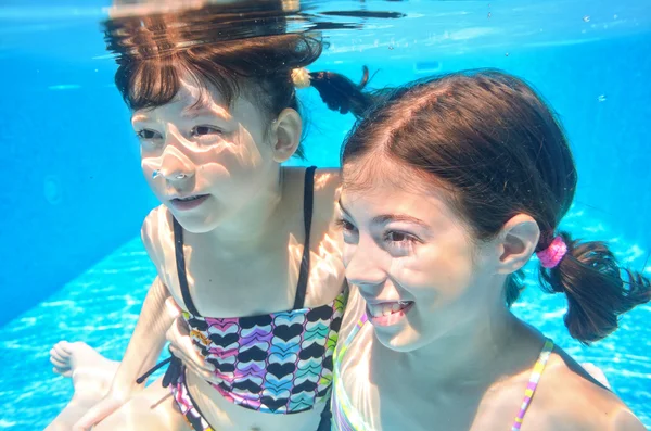 Chicas felices nadan bajo el agua en la piscina —  Fotos de Stock