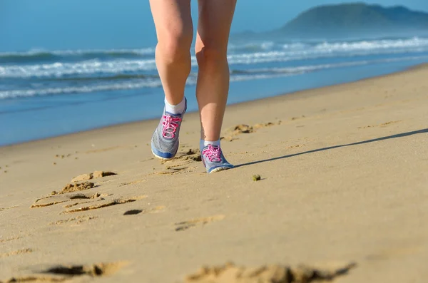 Femme coureur jambes dans des chaussures sur la plage — Photo