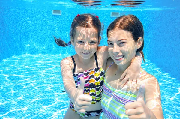 Niños activos felices nadan en la piscina y juegan bajo el agua —  Fotos de Stock