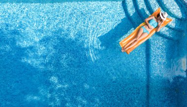 Yüzme havuzunda dinlenen güzel genç bir kadın, şişme yatakta yüzen ve aile tatilinde suda eğlenen bir kız, tropikal tatil beldesi, yukarıdan drone manzarası