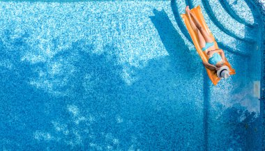 Yüzme havuzunda dinlenen güzel genç bir kadın, şişme yatakta yüzen ve aile tatilinde suda eğlenen bir kız, tropikal tatil beldesi, yukarıdan drone manzarası