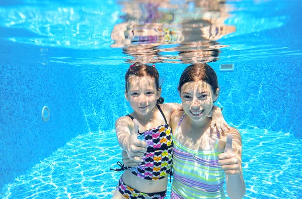 Niños activos felices nadan en la piscina y juegan bajo el agua —  Fotos de Stock
