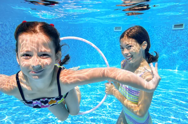 Fröhliche aktive Kinder schwimmen im Pool und spielen unter Wasser — Stockfoto