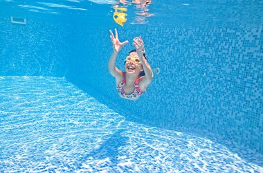 Çocuk yüzme havuzunda su altında yüzüyor, aktif kız suya dalıyor ve su altında eğleniyor, çocuk fitness ve aile tatilinde spor yapıyor. 