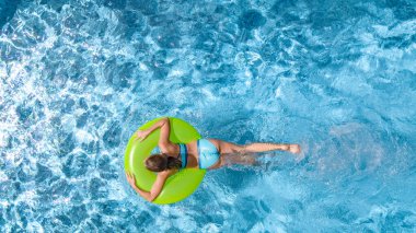 Yüzme havuzundaki aktif genç kız yukarıdan havuz manzaralı, çocuk gevşiyor ve şişme halka donutla yüzüyor ve aile tatilinde suda eğleniyor, tropikal tatil beldesi