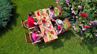 Aile ve arkadaşlar yaz bahçe partisinde dışarıda birlikte yemek yiyorlar. Yukarıdan yiyecek ve içeceklerle dolu bir masa manzarası. Tatil, tatil ve piknik konsepti.