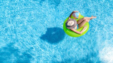 Yüzme havuzundaki aktif genç kız yukarıdan havuz manzaralı, genç kız gevşiyor ve şişme halka donutla yüzüyor ve aile tatilinde suda eğleniyor, tropikal tatil beldesi