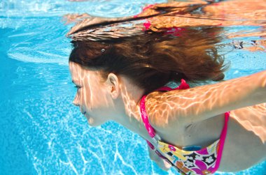 Çocuk yüzme havuzunda su altında yüzüyor, aktif küçük kız suya dalıyor ve su altında eğleniyor, çocuk fitness ve aile tatilinde spor yapıyor. 