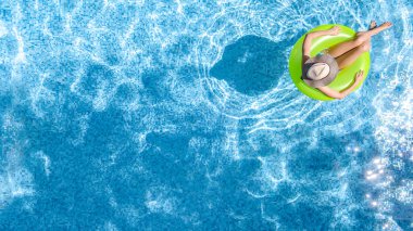 Yüzme havuzundaki aktif genç kız yukarıdan drone görüntüsü, genç kız gevşiyor ve şişme halka donutla yüzüyor ve aile tatilinde suda eğleniyor, tropikal tatil beldesi