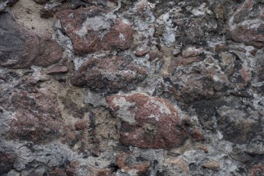 Kale, eski bir taş bina. Çimento ve alçı izleri olan büyük kayalar. Koyu griler, siyahlar, kahverengiler ve bordo renkleri. Gün ışığı.