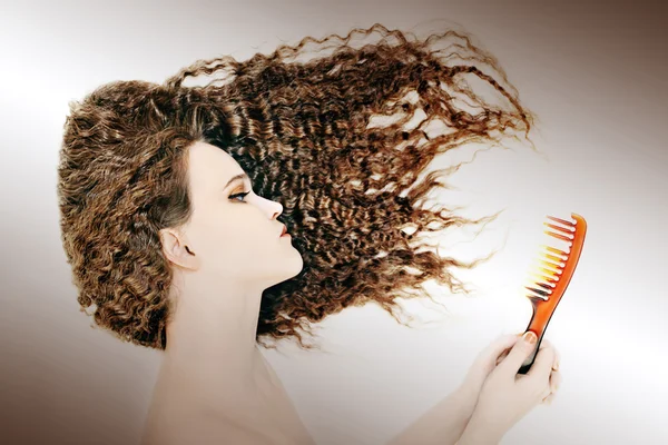 Кудрявая женщина расчесывает волосы — стоковое фото